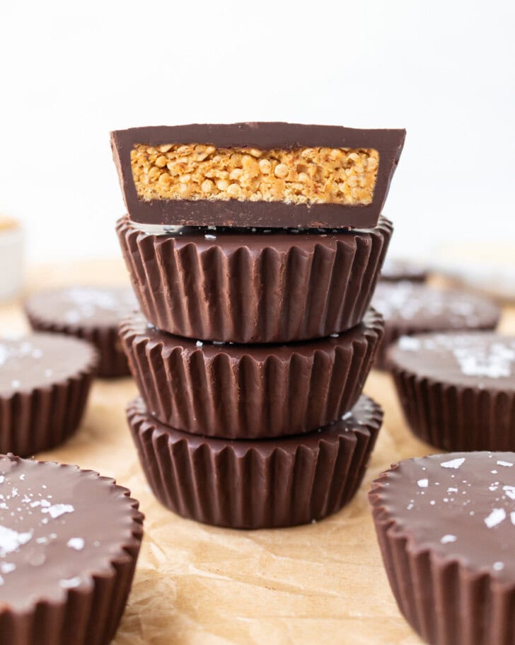 A stack of four chocolate peanut butter cups with the top one cut in half