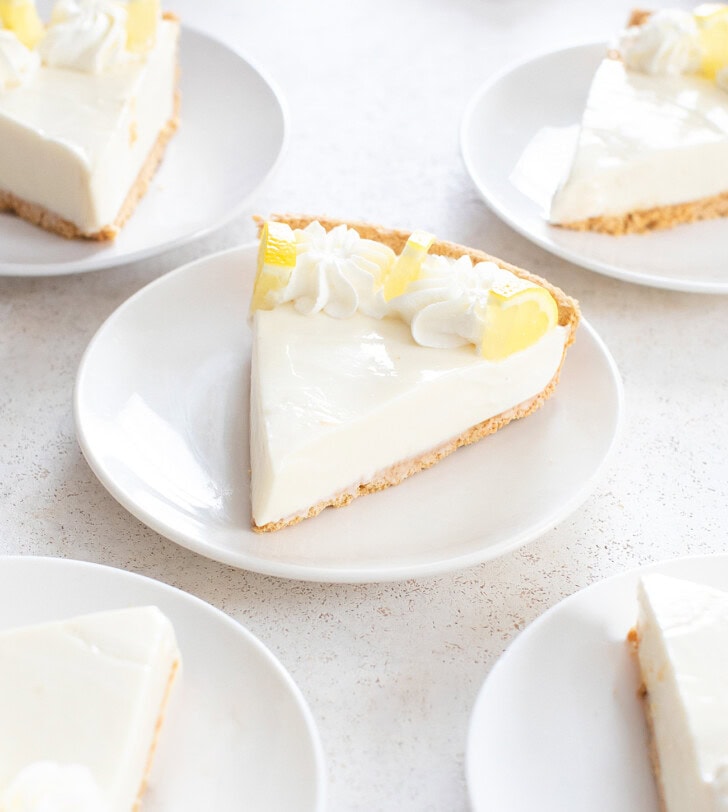 Lemon pie slices with whipped cream and fresh lemon pieces on top