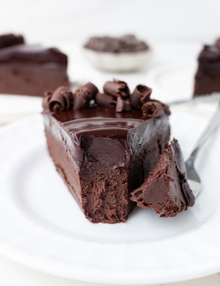 A bite of cake on a fork taken from a slice of chocolate cake