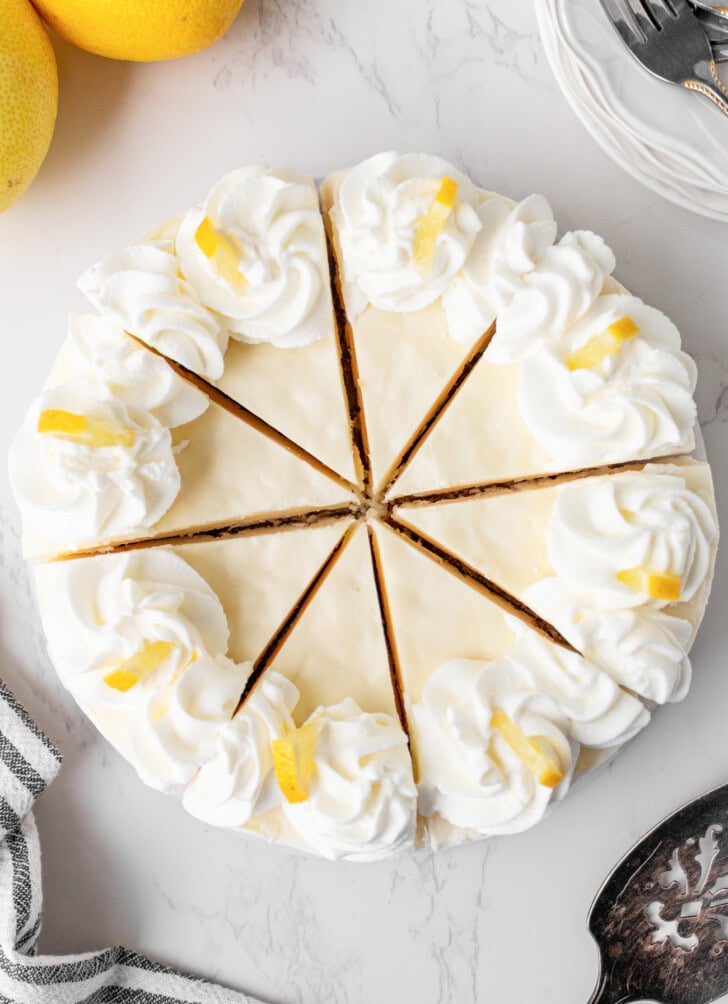 A cheesecake decorated with whipped cream and lemon slices
