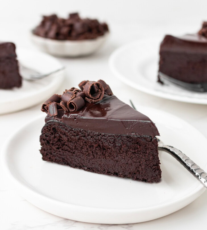 A side view of a slice of chocolate cake on a white plate
