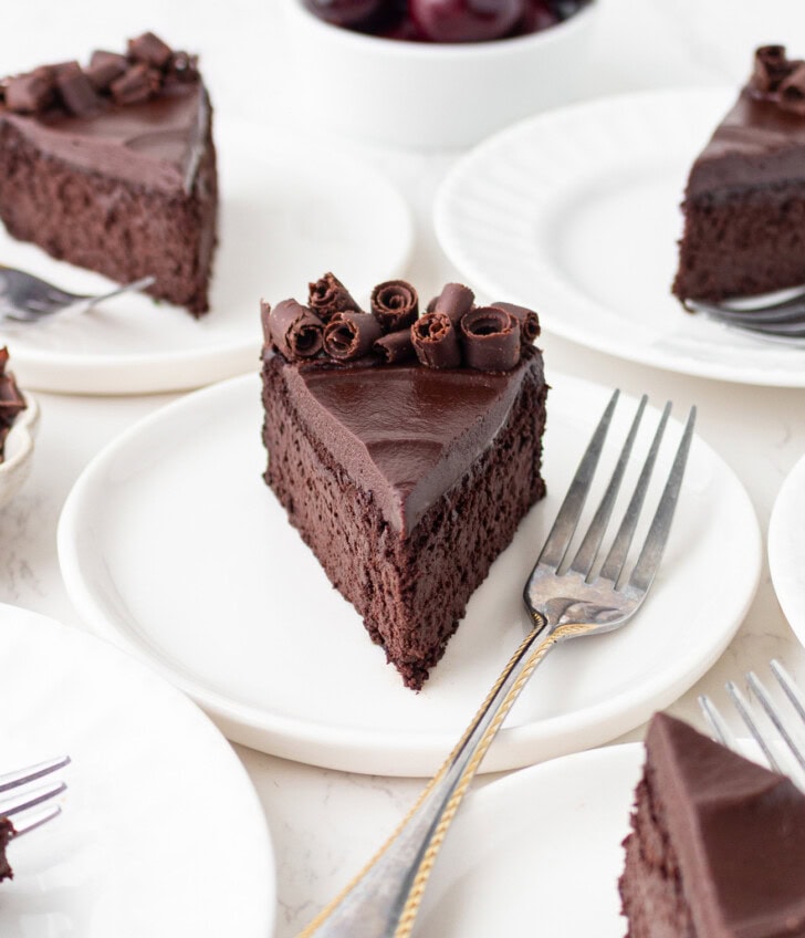 A slice of chocolate cake on a white plate with a silver fork